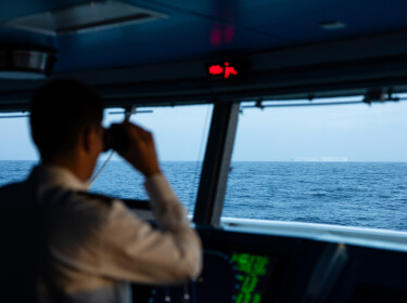 le capitaine sur la passerelle regarde dans ses jumelles