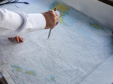 Le capitaine trace au compas sur la carte